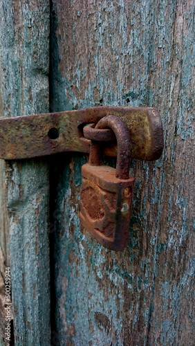 The rusty padlock and old wood paint has peeled off