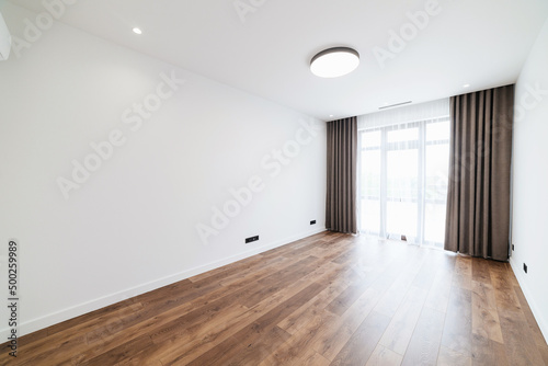 Spacious  large  empty room with a large window and wood floors