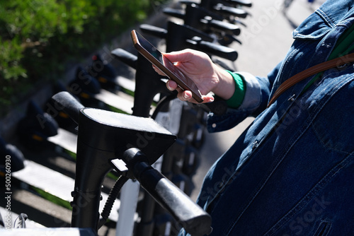 Woman renting scooter using app on her mobile phone closeup photo