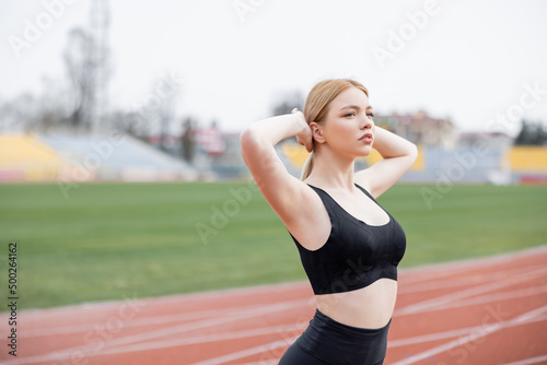 young sportive woman in black sports bra warming up with hands behind head. © LIGHTFIELD STUDIOS