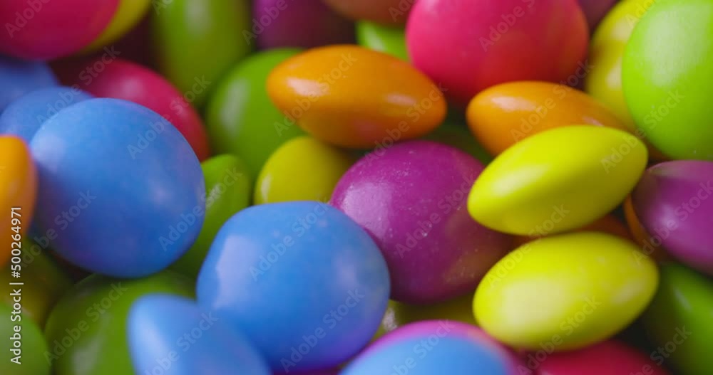 Slow motion close-up of round colorfull chocolate candies, dragee. Rotation and fall multicolored chocolate candies Slow motion close-up of round colorfull chocolate candies, dragee. Rotation and fall multicolored chocolate candies