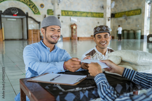 portrait of happy muslim man giving zakat charity for eid mubarak at the mosque photo