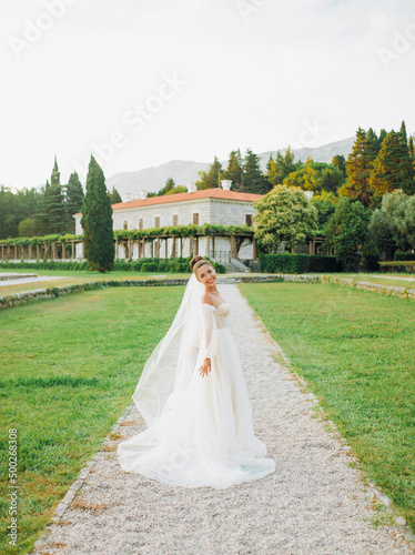 Portrait of the bride in a cream dress on the background of a luxurious mansion.