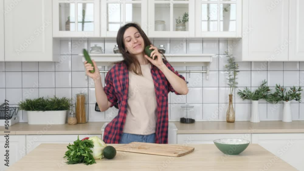 Young happy woman dancing, cooking at home, preparing a healthy lunch, listening to music in the modern kitchen Young happy woman dancing, cooking at home, preparing a healthy lunch, listening to music in the modern kitchen