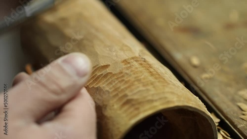 carver cuts wooden detail on woodworking chisel
