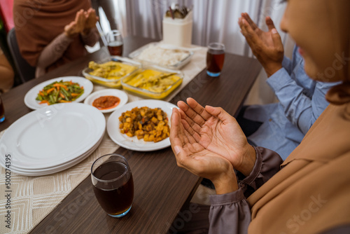 muslim people praying before break fasting iftar dinner together at home in ramadan celebration