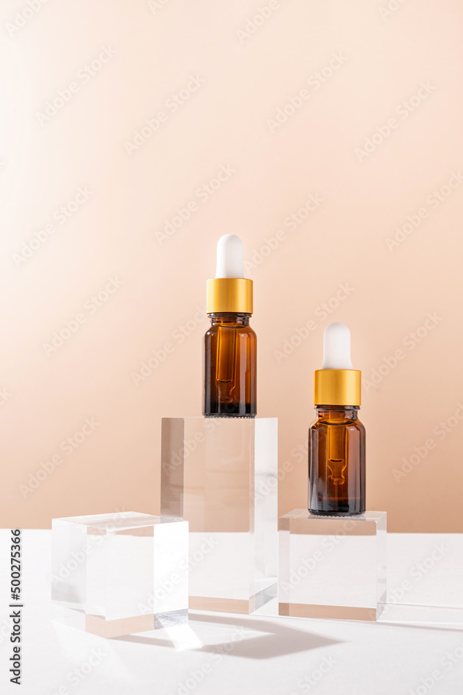 Amber glass dropper bottles with a pippette with white rubber tip on glass podium and beige background, mockup design Amber glass dropper bottles with a pippette with white rubber tip on glass podium and beige background, mockup design