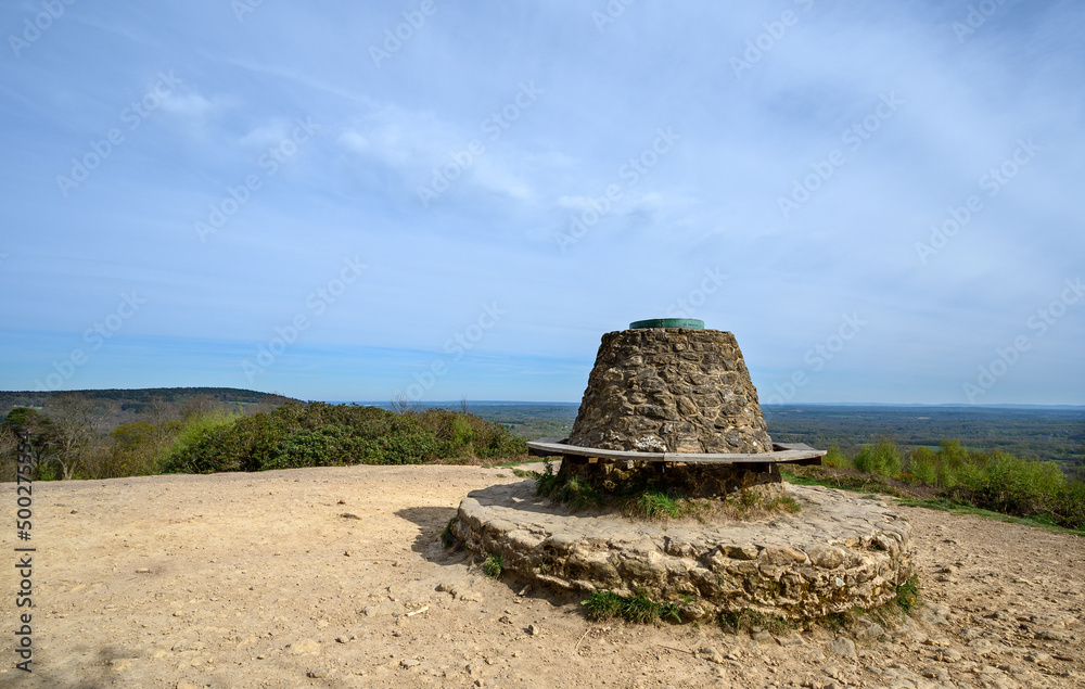 Holmbury Hill, Surrey, UK: The summit marker at the top of Holmbury Hill part of the Surrey Hills Area of Outstanding Natural Beauty. View of countryside looking south over Surrey and Sussex.