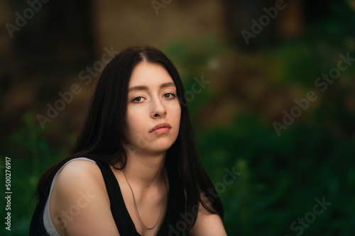 portrait of a beautiful sad young girl on a background of greenery