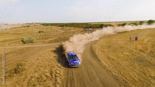 Low Flying Aerial Of Subaru Rally Car Drifting Around A Corner With Dust Flying photo