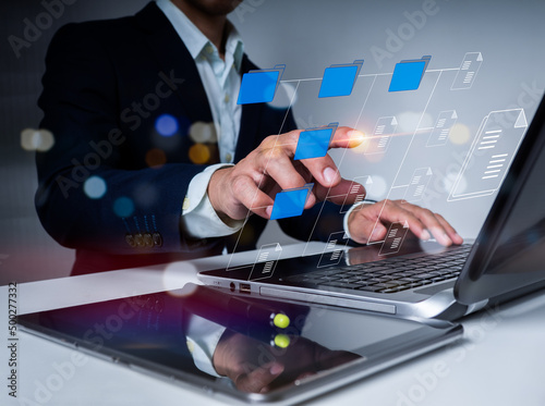 The businessman is using a laptop computer. To properly handle files, knowledge, and documentation in an ERP-enabled firm, use a Document Management System (DMS), an online documentation database.