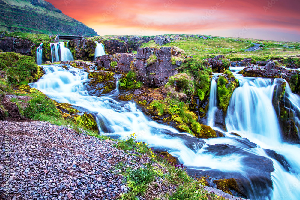 Beautiful scenery with a waterfall Kirkjufell and yellow flowers at dawn in Iceland. Exotic countries. Amazing places. Popular tourist atraction. (Meditation, antistress - concept).