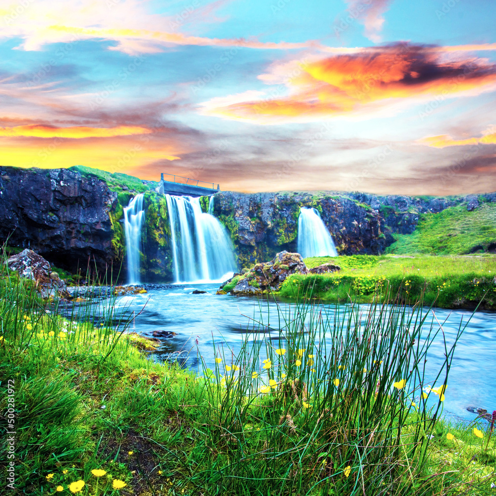 Beautiful scenery with a waterfall Kirkjufell and yellow flowers at dawn in Iceland. Exotic countries. Amazing places. Popular tourist atraction. (Meditation, antistress - concept).