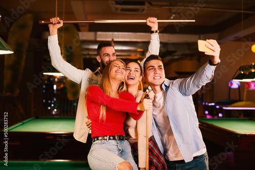 Group of young people having fun in a night out in billiards club and taking selfie