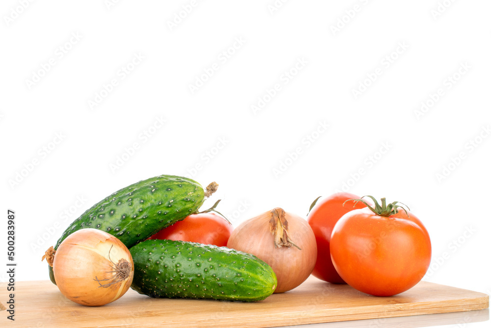 Three ripe tomatoes, two onions and two cucumbers on a wooden cutting board, macro, isolated on a white background. Three ripe tomatoes, two onions and two cucumbers on a wooden cutting board, macro, isolated on a white background.