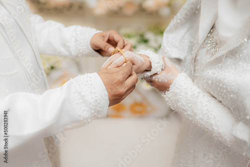 A man puts a bracelet on his partner's hand during a wedding in Lhokseumawe City, Aceh. Pernikahan di Aceh. photo