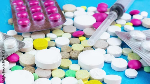 Assorted pharmaceutical medicine pills, tablets and capsules over blue background