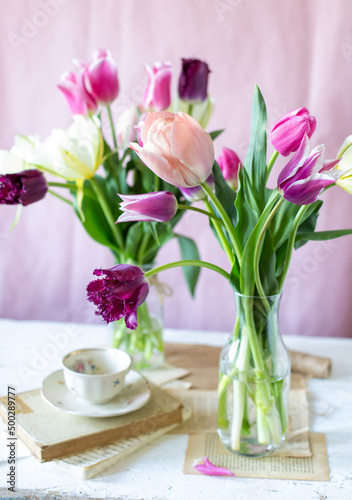 Mazzi di tulipani dalle sfumature del rosa su bottiglie di vetro sopra un tavolo di legno 