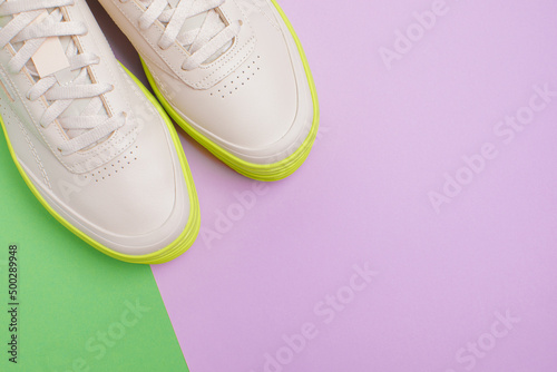 beige neon-soled sneakers on color background - Image