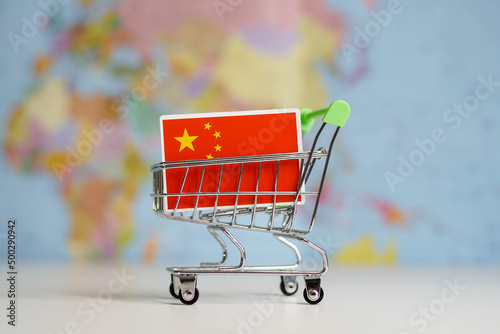 China national flag in miniature shopping trolley cart. Shopping online or shipping  duty concept. World map on the background.
