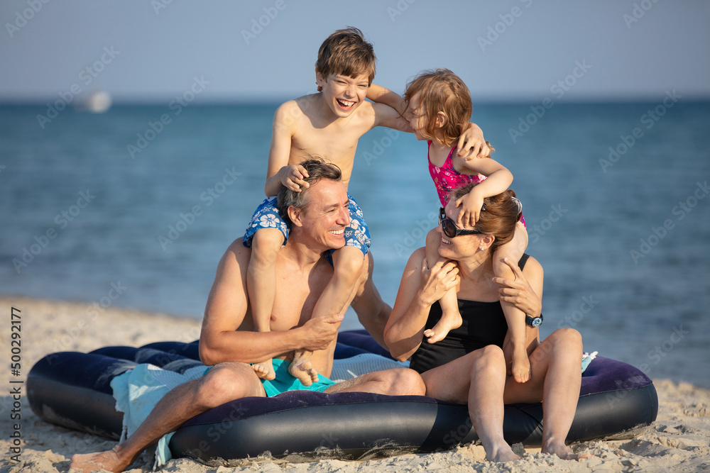 Happy family of four having fun on the beach Happy family of four having fun on the beach