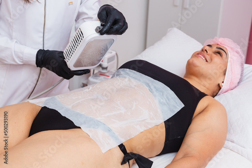 Application of cryolipolysis, cryotherapy, preparing to apply to the patient's abdomen, with a single plate of the cryolipolysis device. patient smiling photo