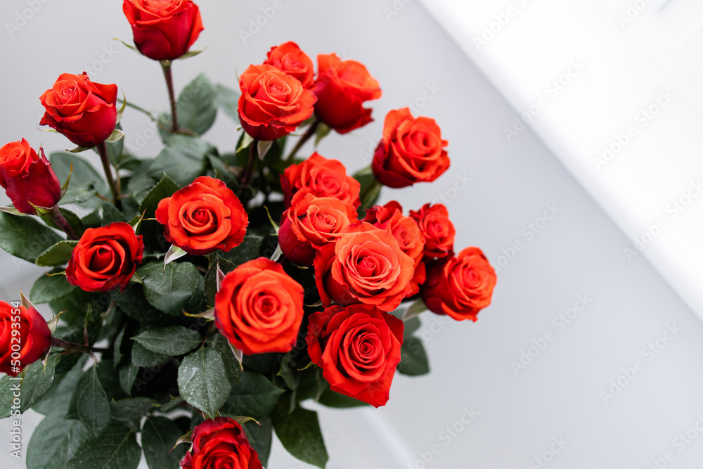 Obraz premium Beautiful bouquet of red roses wedding flowers on white background. Light minimal interior, decoration of apartment, copy space