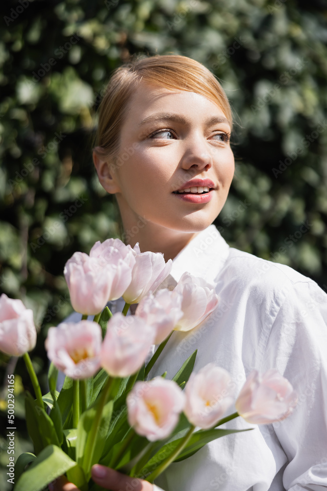 smiling woman with bouquet of tulips looking away outdoors. smiling woman with bouquet of tulips looking away outdoors.