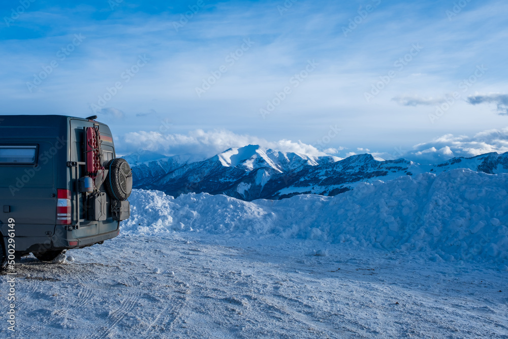 Dirty 4x4 camper van in snowy landscape with incredible clouds behind