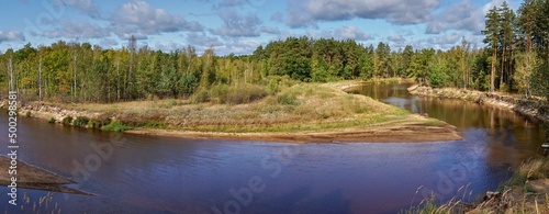 A beautiful forest landscape from an upper angle over a bend in the river on a bright sunny day. Extra wide panorama