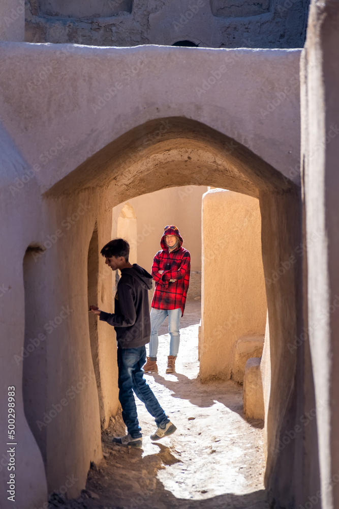 Mother and son walking among the ruins of the adobe village of Kharanaq in Iran