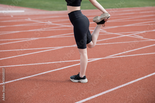cropped view of sportswoman in black bike shorts stretching leg on stadium. © LIGHTFIELD STUDIOS
