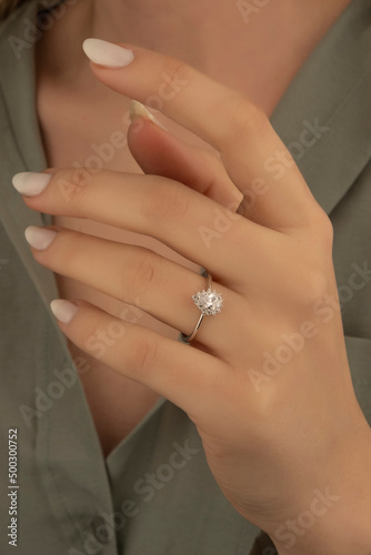 Beautiful lady s hand. woman wearing a white blouse and a diamond ring on her finger.