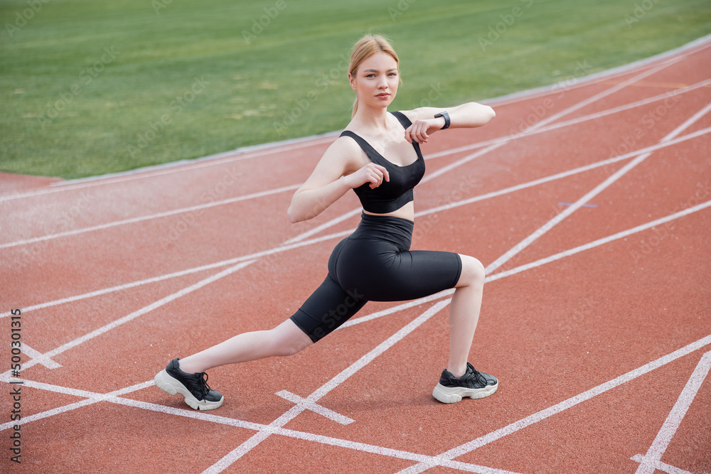 full length view of young sportive woman exercising on stadium.