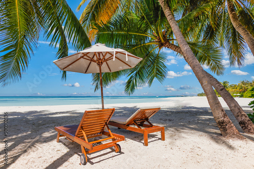 Tropical beach nature as summer landscape with couple chairs, beds under palm trees, calm sea sky for beach. Luxury travel landscape, beautiful honeymoon destination for vacation holiday. Beach coast