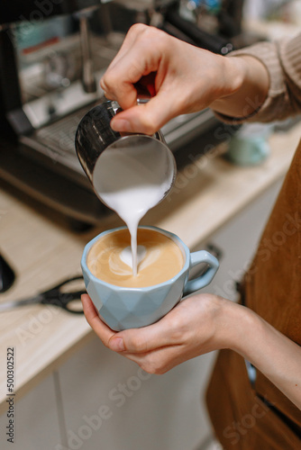 The hand of a barista girl pouring milk into coffee. Cafe, breakfast, morning