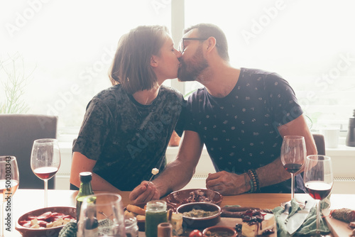 couple kissing - man and woman sitting at table with finger food - love eat dating concept photo