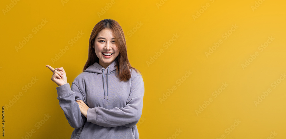 Portrait of Asian woman gesturing pointing at empty space for ad text, portrait concept used for advertisement and signage, isolated over yellow background, copy space. Portrait of Asian woman gesturing pointing at empty space for ad text, portrait concept used for advertisement and signage, isolated over yellow background, copy space.