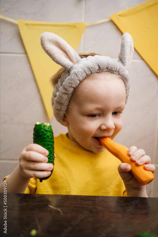 baby in rabbit ears eats vegetables carrot cucumber Easter baby in rabbit ears eats vegetables carrot cucumber Easter