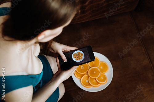 Woman in dress taking food photos on her smartphone. Food blogger concept. 