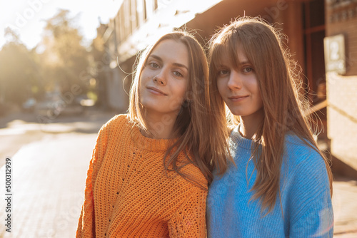 Beautiful twins sister with long blonde hair looking at camera and smiling