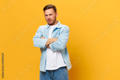 Sad frustrated tanned handsome man in blue basic t-shirt think about problem at work fold arms posing isolated on yellow studio background. Copy space Banner Mockup. People emotions Lifestyle concept