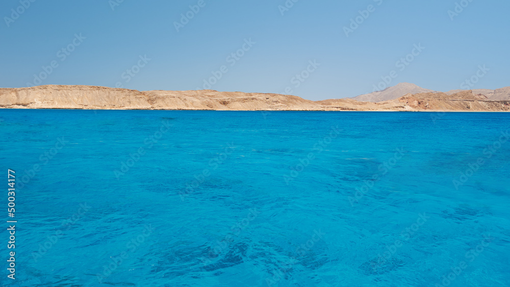 Blue sky and sea background. View from the ocean to the shore