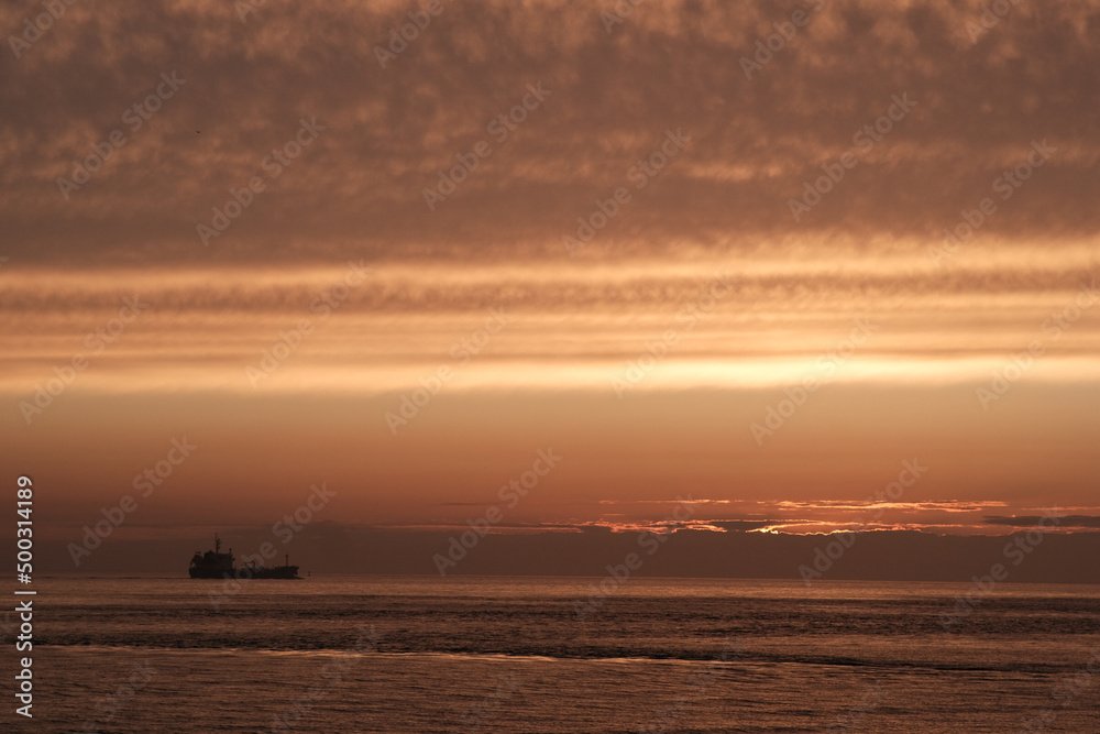 industry ship driving into dramatic ocean sunset