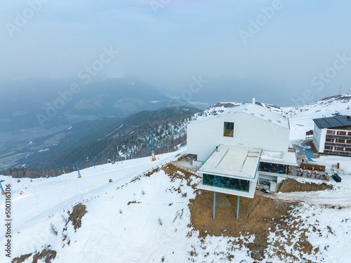 Aerial view of lumen museum and restaurant on snow covered landscape. White modern architecture on mountain against sky in alps. Beautiful alpine tourist attraction during winter.