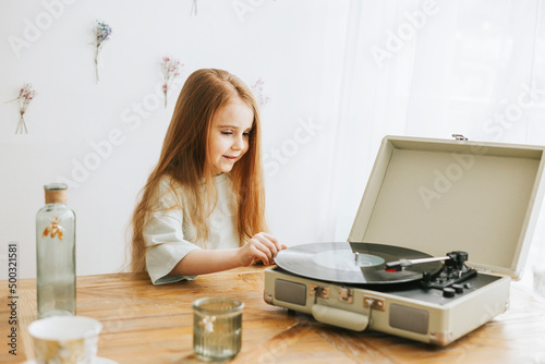 little red haired girl near record player in kitchen of rustic country house with beautiful vintage decor, a happy todler girl in spring, earth tone colors