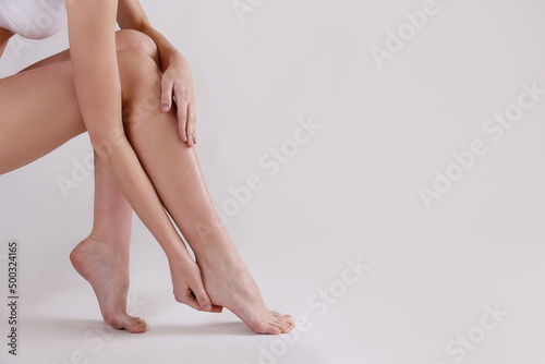 Cropped shot of woman's legs after body hair removal procedures. Unrecognizable woman showing her calves over isolated white background. Copy space for text, close up. photo