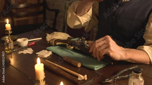 A man from the 1700s takes a sip of coffee before he starts the process of cleaning his flintlock pistol.