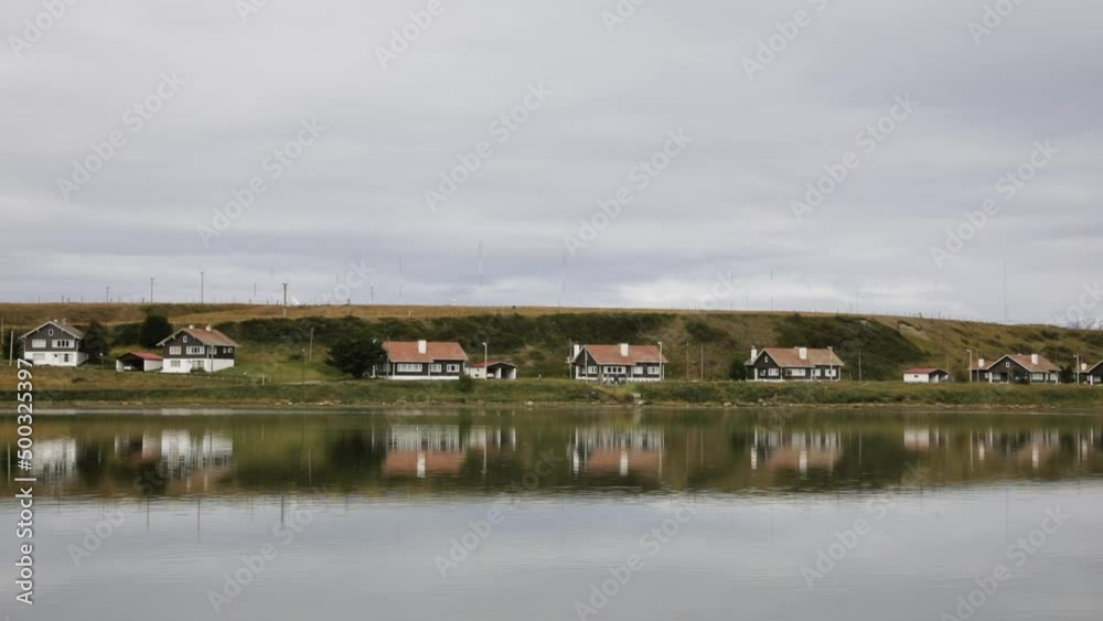 Panorama view of houses in the seashore. View of the buildings reflection in the sea water in Ushuaia, Tierra del Fuego, Patagonia Argentina. Panorama view of houses in the seashore. View of the buildings reflection in the sea water in Ushuaia, Tierra del Fuego, Patagonia Argentina.