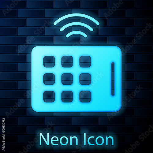 Glowing neon Wireless tablet icon isolated on brick wall background. Internet of things concept with wireless connection. Vector